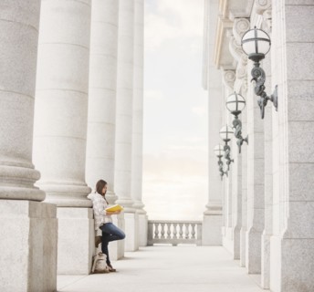 Caucasian woman leaning on pillar reading notebook