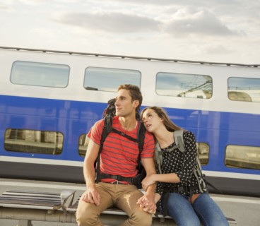 Caucasian couple sitting on bench near train