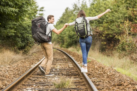 Caucasian couple balancing on train tracks