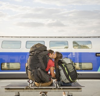Caucasian couple kissing on bench near train
