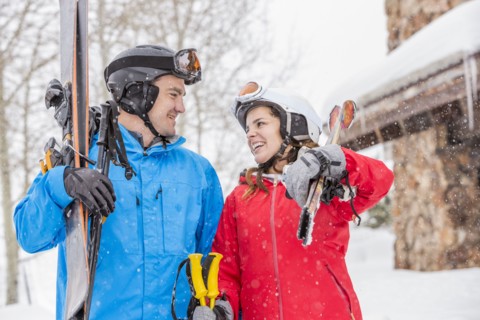 Smiling Caucasian couple carrying skis