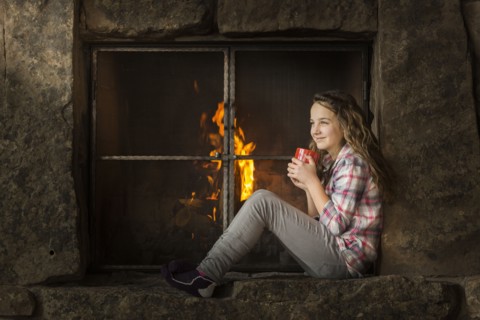 Smiling Caucasian girl sitting near fireplace