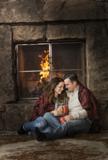 Smiling Caucasian couple cuddling on floor near fireplace