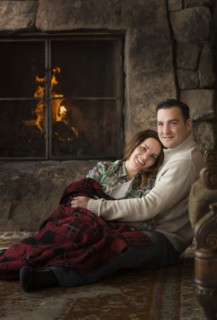 Smiling Caucasian couple cuddling on floor near fireplace