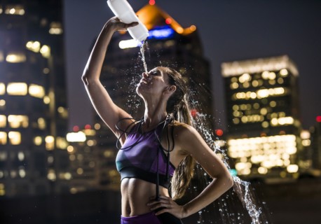 Caucasian woman spraying water on face in city at night