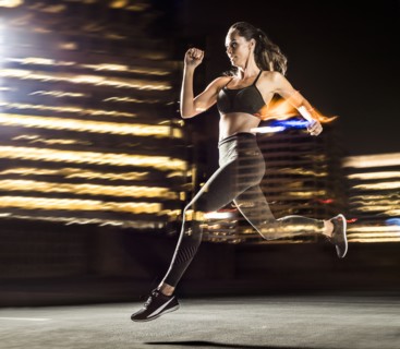 Double exposure of Caucasian woman running in city at night