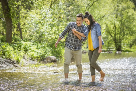 Couple holding hands wading in river
