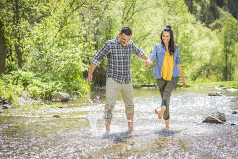 Woman kicking water on man in river