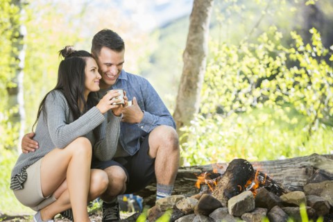 Couple drinking coffee near campfire