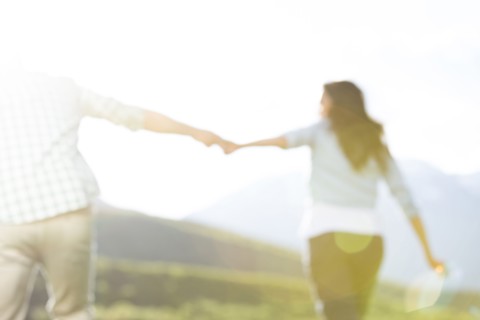 Defocused couple holding hands walking near mountain
