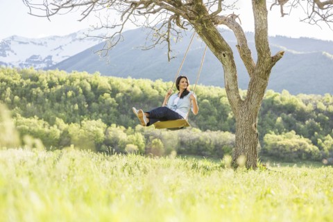 Caucasian woman swinging on tree swing