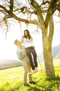 Man holding woman on tree swing