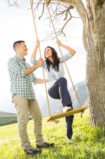 Man helping woman on tree swing