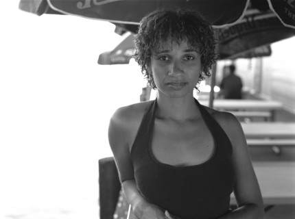 Mixed race woman sitting under umbrella in cafe