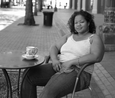 Mixed race woman drinking coffee at sidewalk cafe