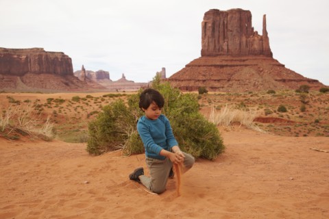 Mixed race boy playing in dirt in Monument Valley