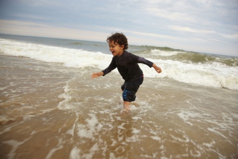 Mixed race boy playing in ocean waves