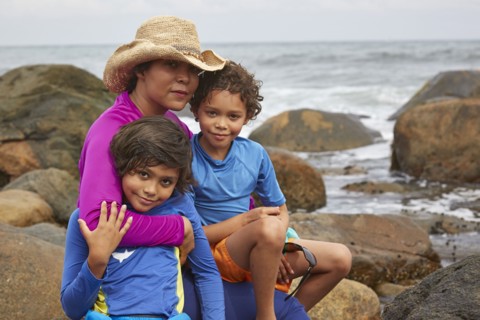 Mother and children hugging on rocky beach