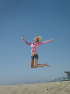 Caucasian woman jumping on beach