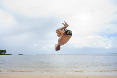 Caucasian man doing a flip on beach
