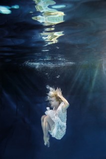 Caucasian woman in dress swimming under water