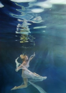 Caucasian woman in dress swimming under water