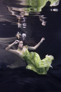 Mixed race woman in dress swimming under water