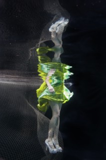 Caucasian woman in dress swimming under water