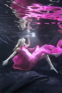 Caucasian woman in dress swimming under water