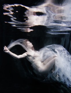 Caucasian woman in scarf swimming under water