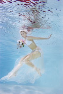 Caucasian bride in bikini swimming under water