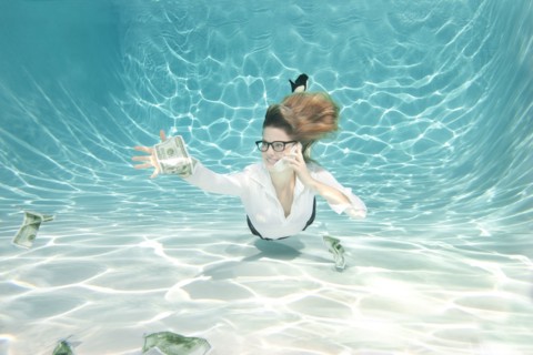 Caucasian businesswoman reaching for money underwater