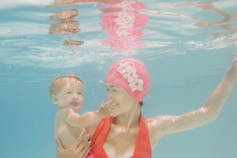 Caucasian mother holding baby underwater
