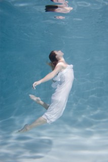 Underwater view of Caucasian woman in dress swimming in pool