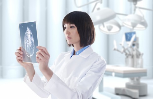 Mixed race doctor looking at digital tablet in operating room