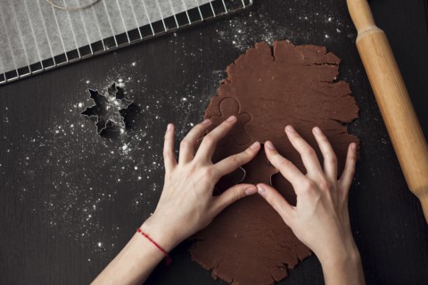 Hand of Caucasian woman pressing pastry cutter into dough