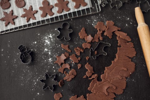 Pastry cutters and gingerbread dough near rolling pin