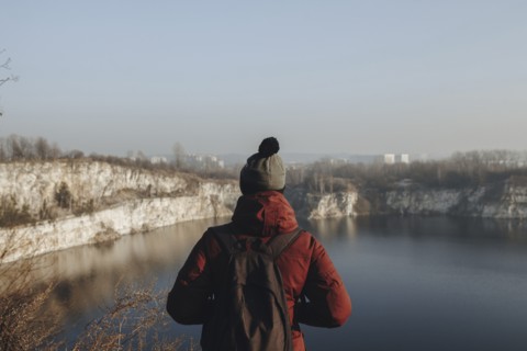Caucasian man at the edge of reservoir wearing backpack