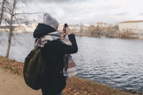 Caucasian woman photographing river with cell phone