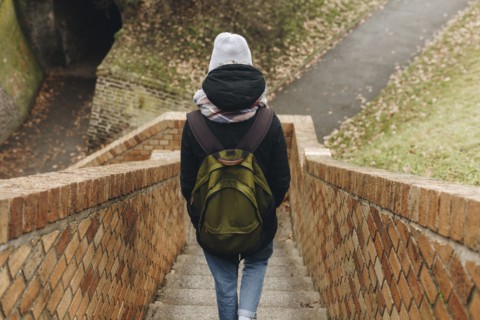 Caucasian woman carrying backpack descending staircase outdoors