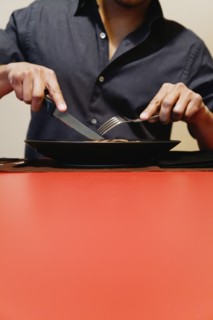 Close up of man cutting meat on plate