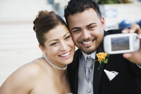 Multi-ethnic bride and groom taking own photograph