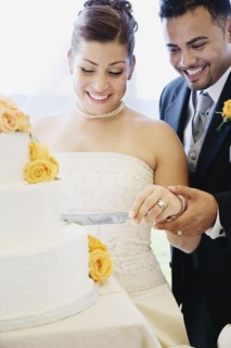 Multi-ethnic bride and groom cutting cake