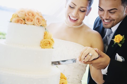 Multi-ethnic bride and groom cutting cake