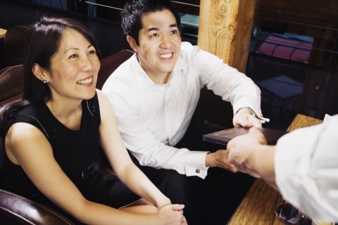 Asian couple paying restaurant bill