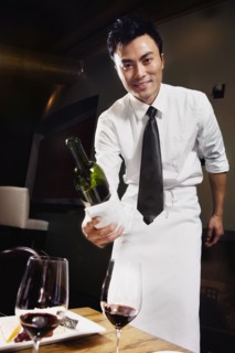 Asian waiter pouring wine