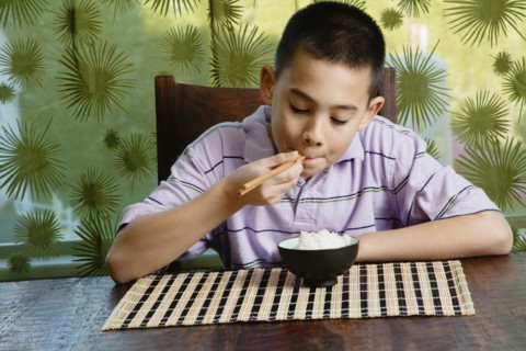 Asian boy eating bowl of rice
