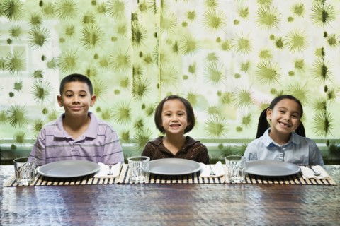 Asian siblings sitting at dinner table