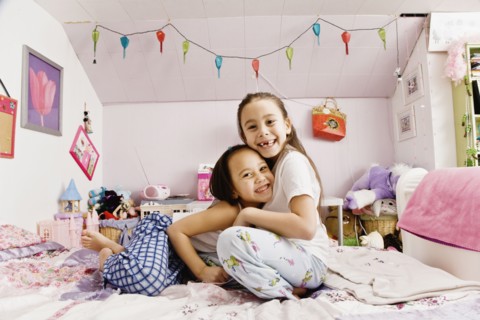 Asian sisters hugging on bed