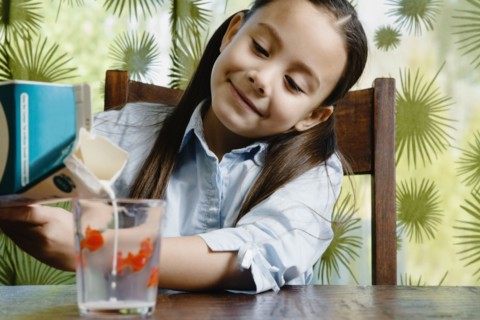 Asian girl pouring glass of milk